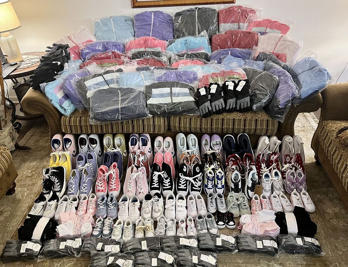 New shoes, jackets, socks and gloves laid out across a sofa and living room floor, each item bagged and labeled with a size, before shipping to Hardeman County, Tennessee.