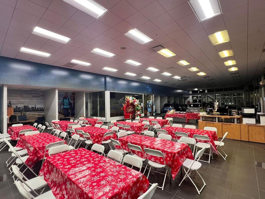 A dealership showroom set with red-covered tables, chairs and a Santa chair before guests arrived